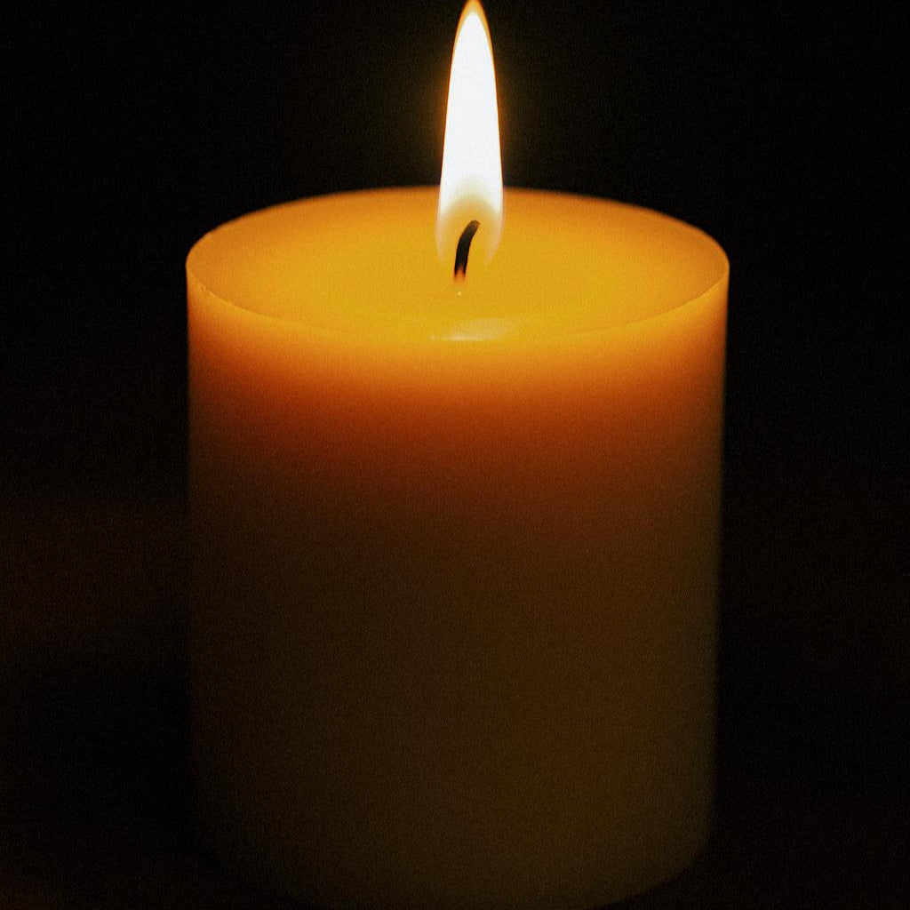 Single lit candle against a black background