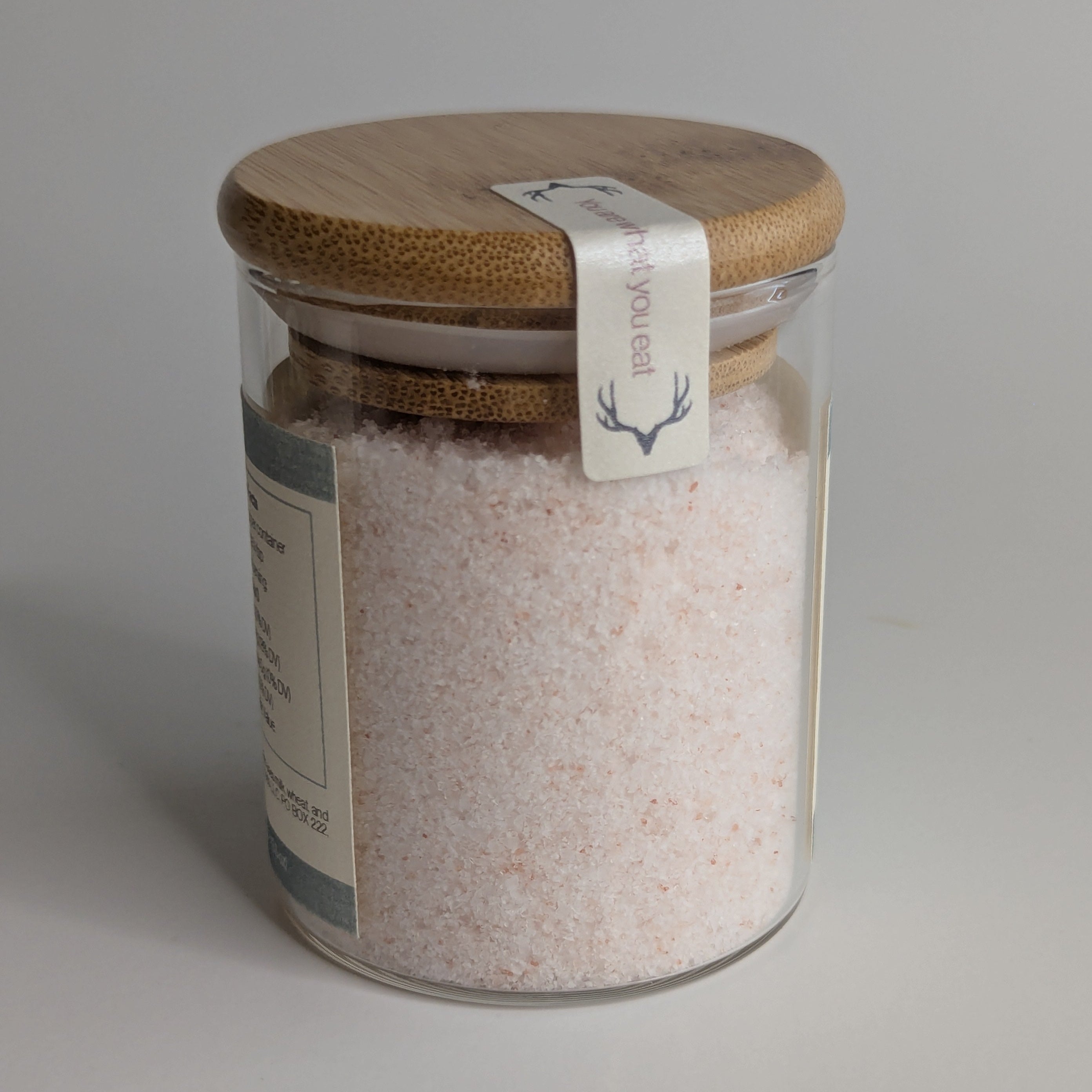 Glass jar with wooden lid and label on a gray background